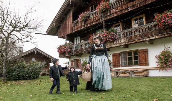 Frau in Schalk mit zwei Kindern auf Blumenwiese. Aus dem Magazin Tracht in Miesbach, © Mathias Leidgschwendner