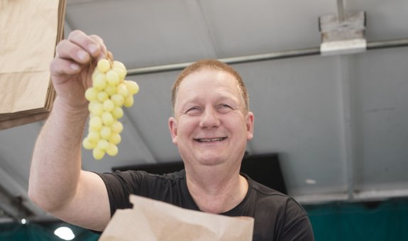 Steffen Schneider steht mit Weintrauben an seinem Stand, &copy; Florian Bachmeier