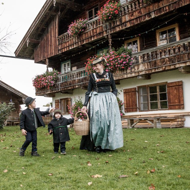 Frau in Schalk mit zwei Kindern auf Blumenwiese. Aus dem Magazin Tracht in Miesbach, © Mathias Leidgschwendner