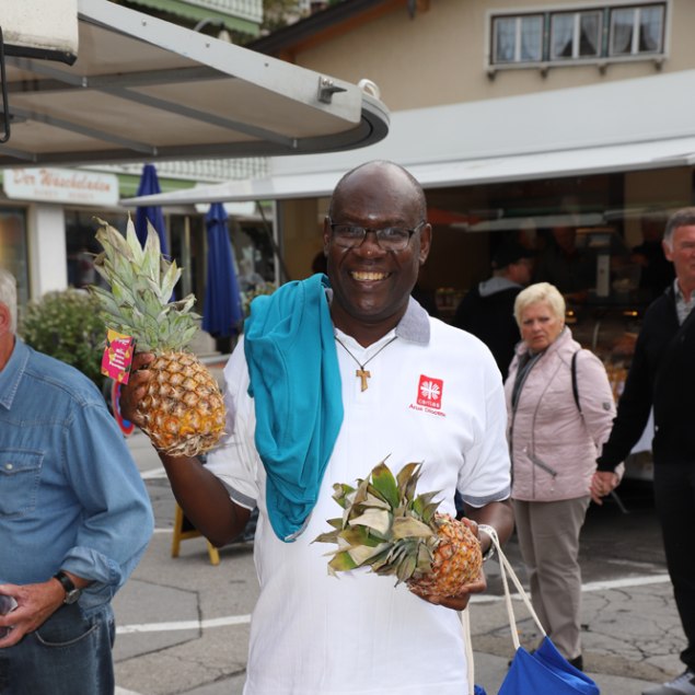 Pater Primus am Marktstand mit einer Ananas in der Hand, © Hartmut Wolf